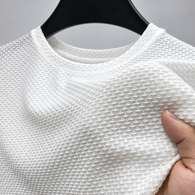 Camisa branca no cabide, com a mão puxando o tecido para mostrar a textura